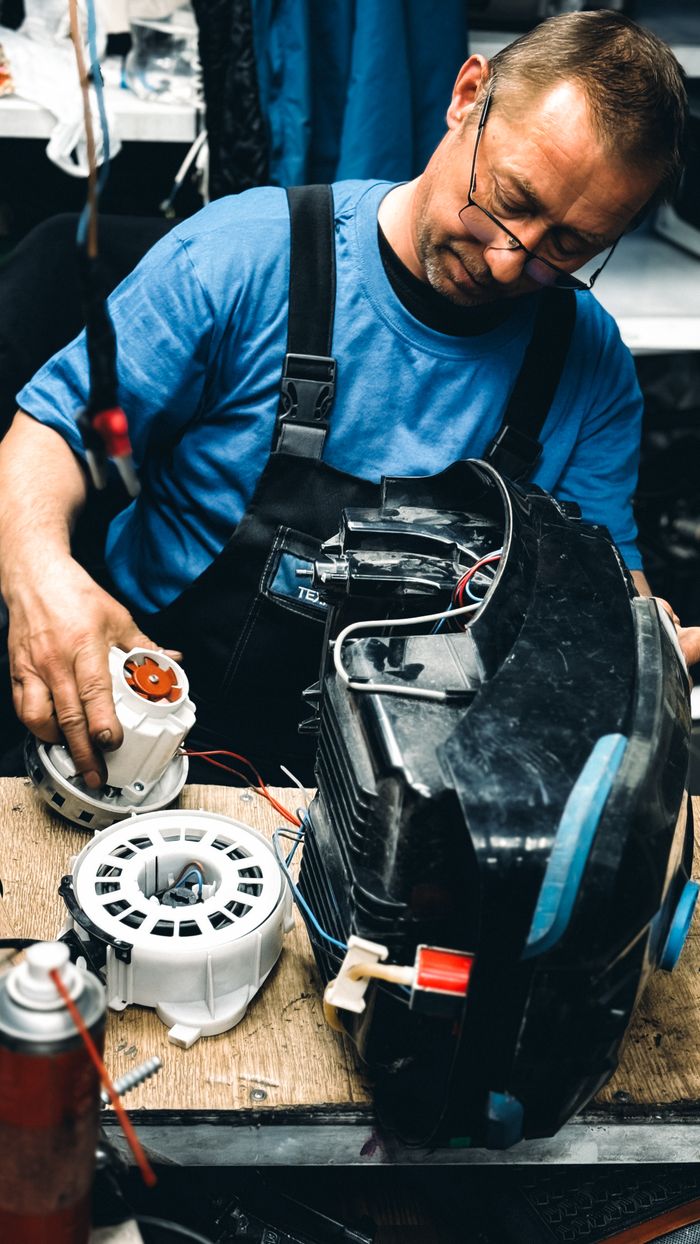 services-02 Experienced technician focused on repairing an electrical machine in a workshop setting.