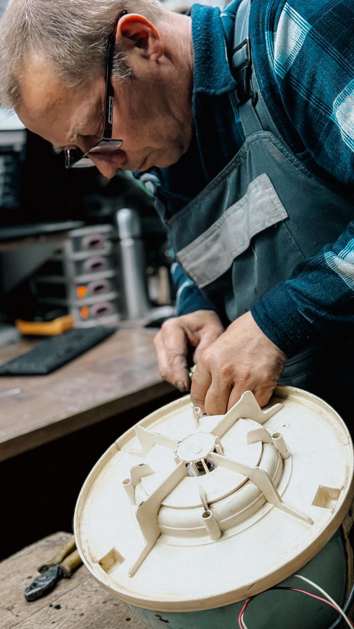 services-01 An experienced technician repairing a component of a home appliance on a workbench.