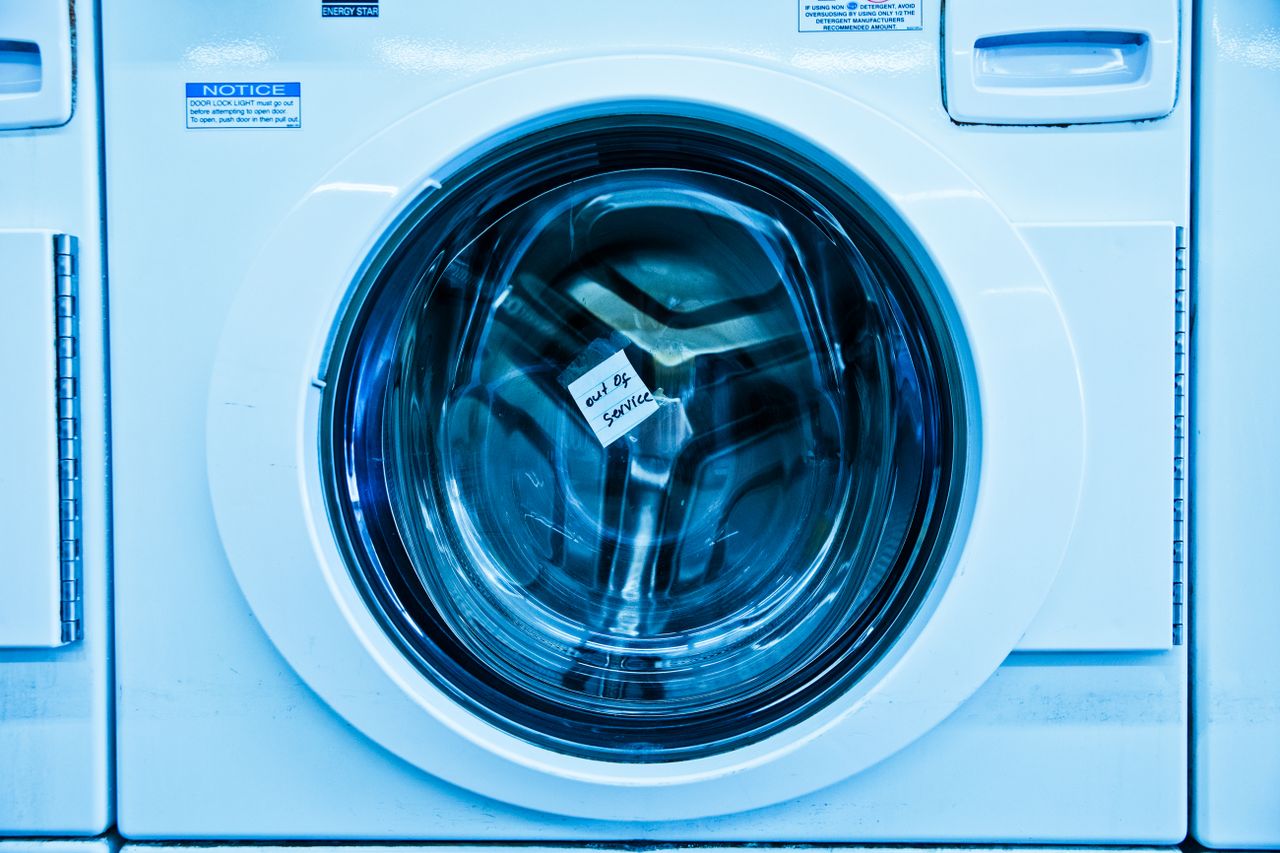 services-03 Close-up of an out-of-service washing machine in a laundromat with a blue tint.