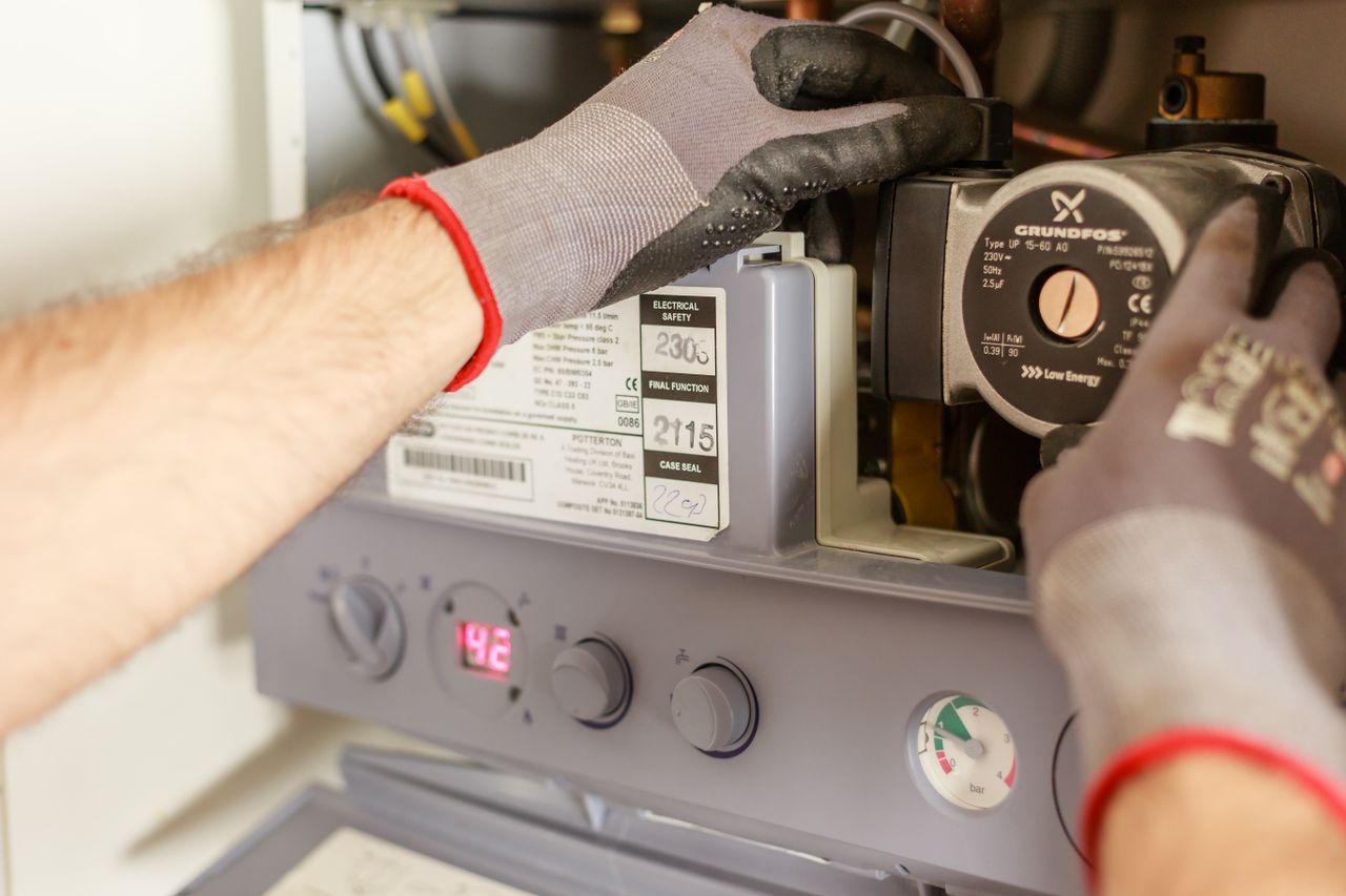 hero-img-01 Close-up of hands adjusting a boiler system with precise instrumentation, showing maintenance work.